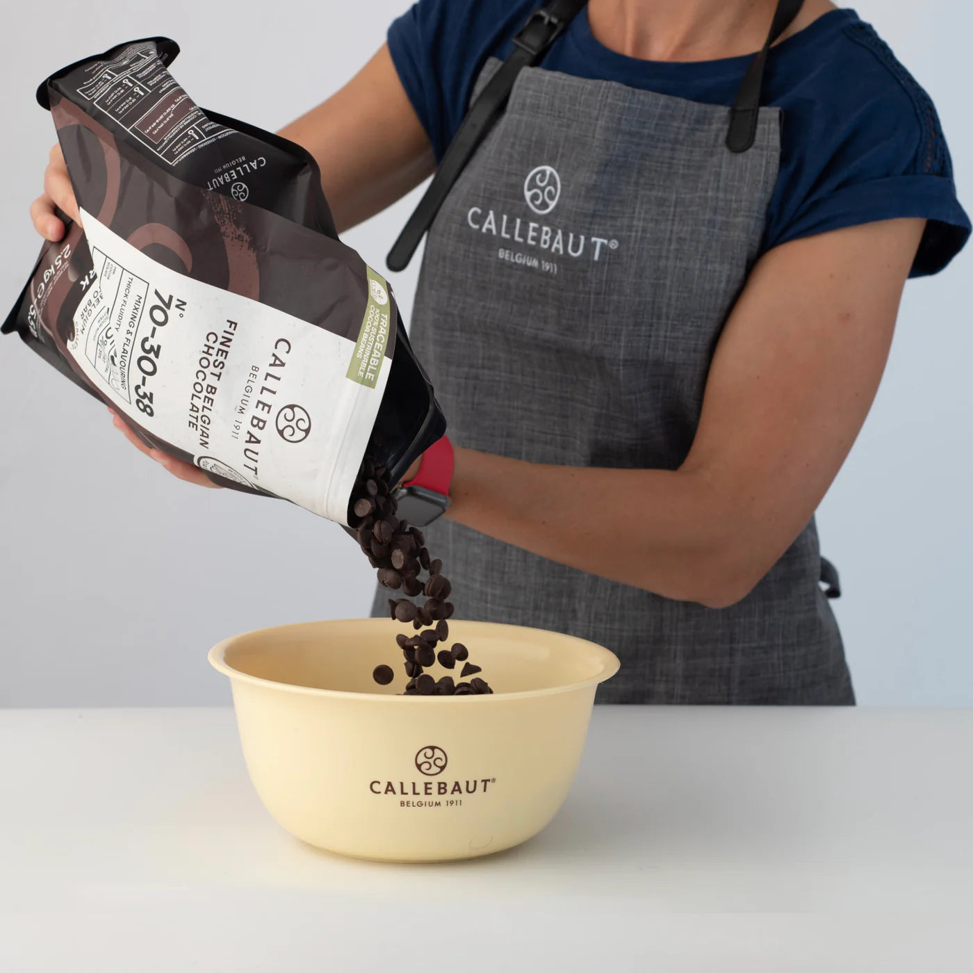 Callebaut chocolatier pouring 70-30-38 dark chocolate callets into a mixing bowl